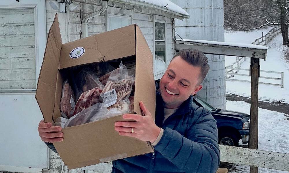 Man holding a box of soy-free & corn-free pastured pork